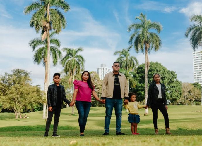 A cheerful family enjoys a sunny day in the park, surrounded by palm trees and lush greenery.