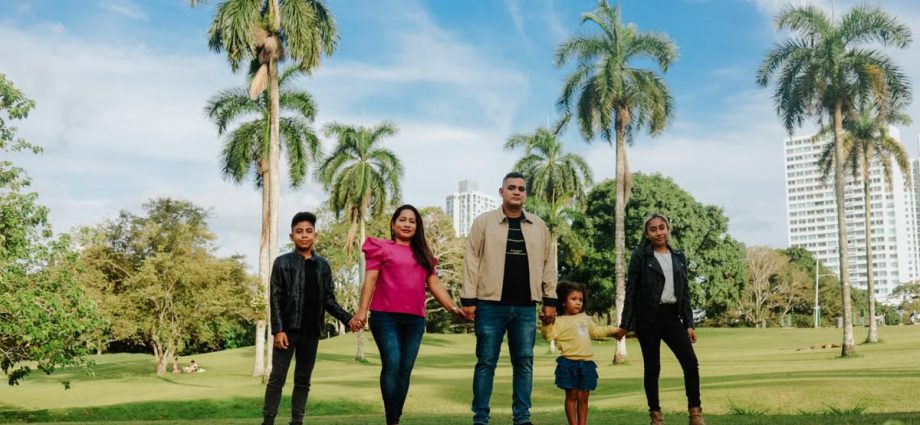 A cheerful family enjoys a sunny day in the park, surrounded by palm trees and lush greenery.